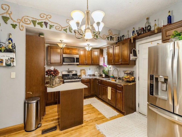 1273 E 18th St, Des Moines, IA 50316 - kitchen with appliances with stainless steel finishes, a sink, light wood-style flooring, a chandelier, and pendant lighting