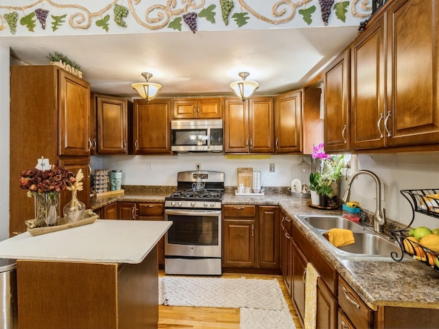 1273 E 18th St, Des Moines, IA 50316 - kitchen with appliances with stainless steel finishes, a sink, light wood finished floors, brown cabinetry, and a peninsula