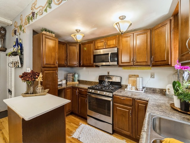 1273 E 18th St, Des Moines, IA 50316 - kitchen featuring appliances with stainless steel finishes, light wood-style floors, a sink, and brown cabinets