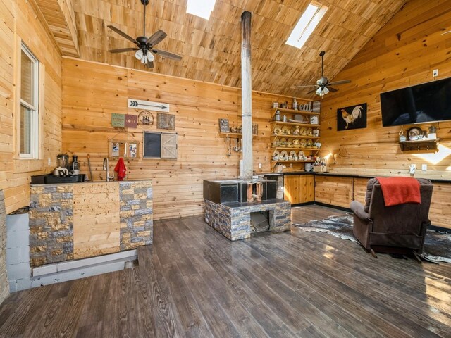 1273 E 18th St, Des Moines, IA 50316 - living room with a ceiling fan, wood walls, wood finished floors, a wood stove, and high vaulted ceiling