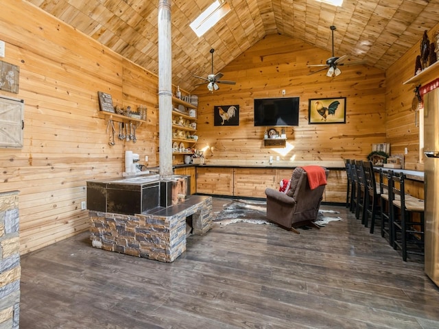 1273 E 18th St, Des Moines, IA 50316 - living room with wooden walls, ceiling fan, a skylight, dark wood finished floors, and high vaulted ceiling