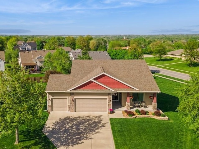 view of front of property with a porch, an attached garage, concrete driveway, and a front lawn