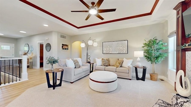 living room featuring a tray ceiling, a ceiling fan, recessed lighting, arched walkways, and baseboards