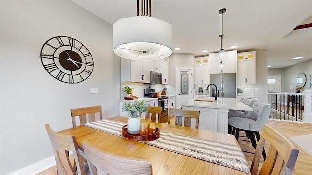 dining space with recessed lighting, light wood-style flooring, and baseboards
