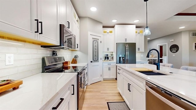 kitchen with appliances with stainless steel finishes, a sink, decorative backsplash, white cabinets, and recessed lighting
