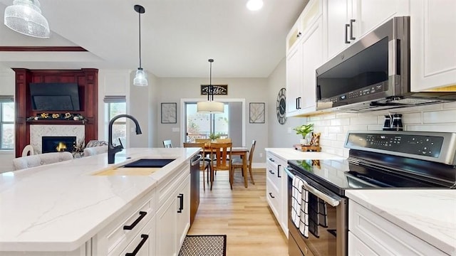kitchen featuring stainless steel appliances, a sink, healthy amount of natural light, light wood-style floors, and recessed lighting