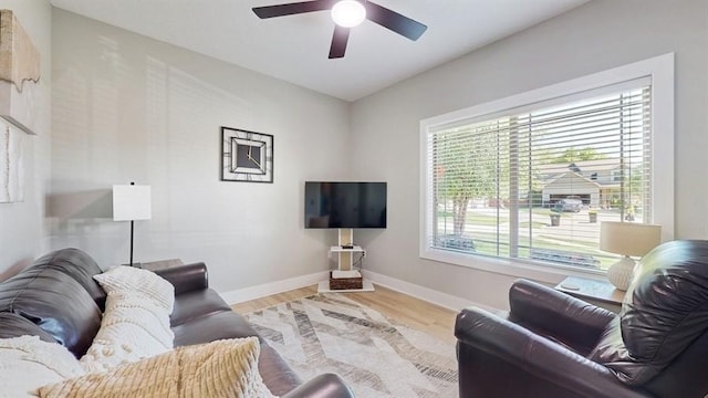 living area with baseboards, ceiling fan, and wood finished floors