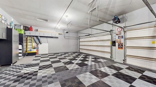 garage featuring freestanding refrigerator and a garage door opener
