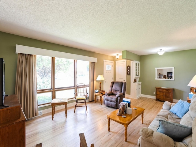 living area featuring a textured ceiling, light wood finished floors, and baseboards
