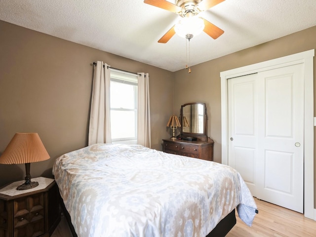 bedroom with a closet, light wood finished floors, and a ceiling fan
