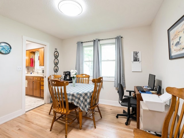 dining area with light wood finished floors, baseboards, and an office area