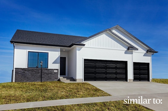 5560 165th St, Urbandale, IA 50323 - modern farmhouse featuring an attached garage, concrete driveway, a front lawn, and stone siding