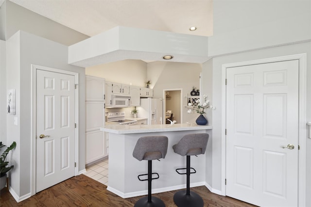 4400 Ep True Pkwy Unit 51, West Des Moines, IA 50265 - kitchen featuring white appliances, a breakfast bar, wood finished floors, white cabinetry, and recessed lighting