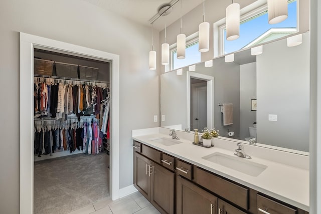 full bath featuring toilet, double vanity, tile patterned flooring, and a walk in closet
