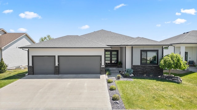 view of front facade with an attached garage, a front lawn, driveway, stone siding, and roof with shingles