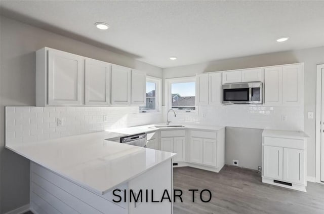 928 Spruce Ave, Norwalk, IA 50211 - kitchen featuring appliances with stainless steel finishes, a peninsula, white cabinetry, wood finished floors, and recessed lighting