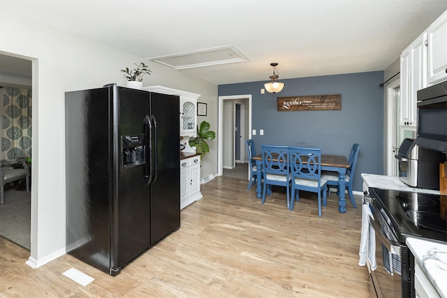 kitchen featuring black refrigerator with ice dispenser, white cabinetry, stainless steel electric range oven, and light wood-style flooring
