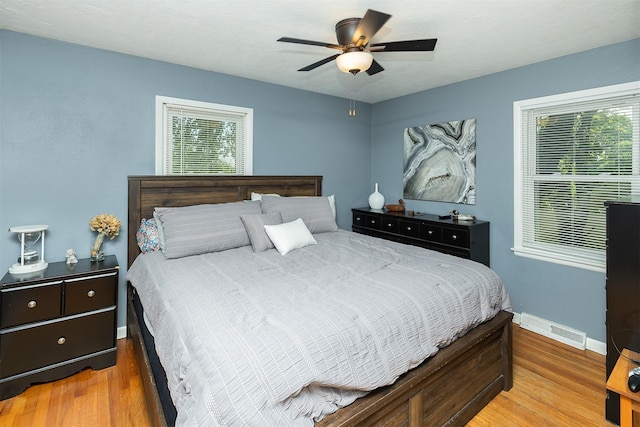 bedroom with baseboards, wood finished floors, and multiple windows