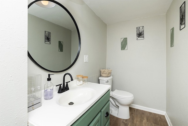 half bathroom with wood finished floors, vanity, toilet, and baseboards