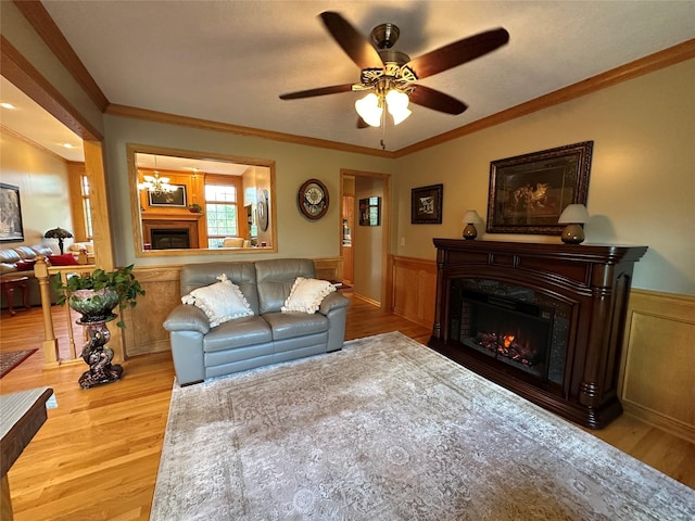 711 E Madison St, Winterset, IA 50273 - living area with a warm lit fireplace, wood finished floors, wainscoting, a ceiling fan, and a chandelier