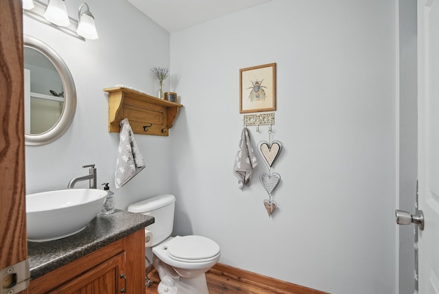 bathroom with toilet, wood finished floors, and vanity