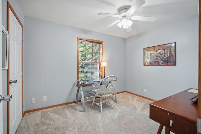 carpeted office space featuring a ceiling fan and baseboards