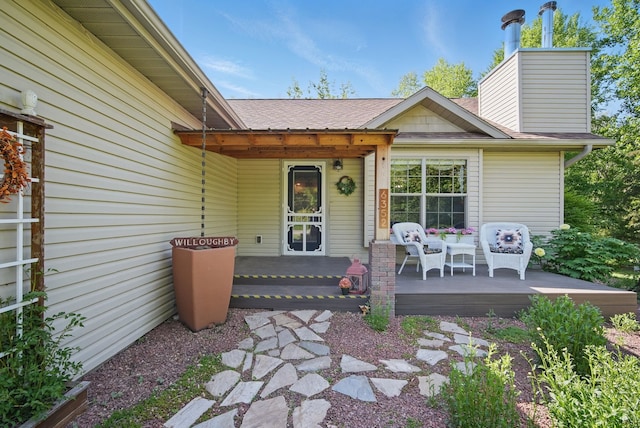 doorway to property with roof with shingles, a chimney, and a porch
