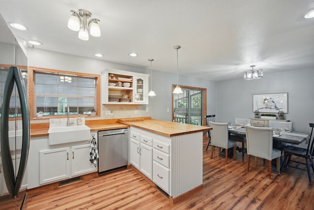 kitchen featuring appliances with stainless steel finishes, wood counters, a sink, a peninsula, and light wood-style floors