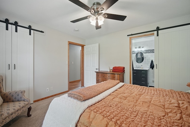 bedroom featuring a barn door, carpet flooring, baseboards, and a ceiling fan