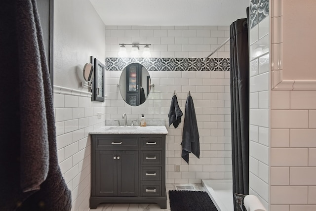 full bathroom with a tile shower, tile walls, and vanity