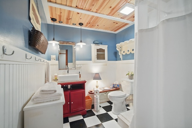 bathroom featuring tile patterned floors, wainscoting, toilet, vanity, and wooden ceiling