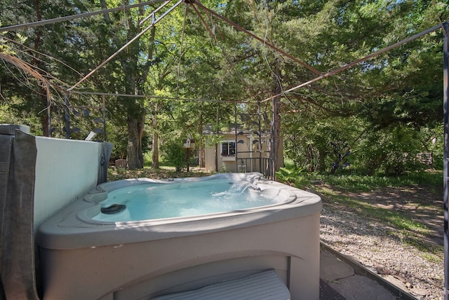 view of swimming pool featuring a hot tub and view of wooded area