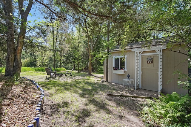 view of yard with a storage unit, an outbuilding, and a fire pit