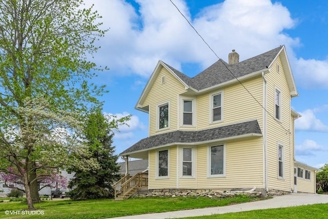 view of front of house featuring a front yard, a chimney, and roof with shingles