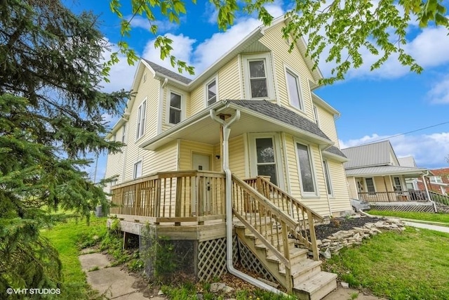 view of front of property with a wooden deck and roof with shingles