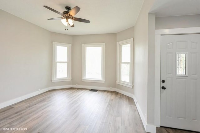 foyer with a ceiling fan, wood finished floors, healthy amount of natural light, and baseboards