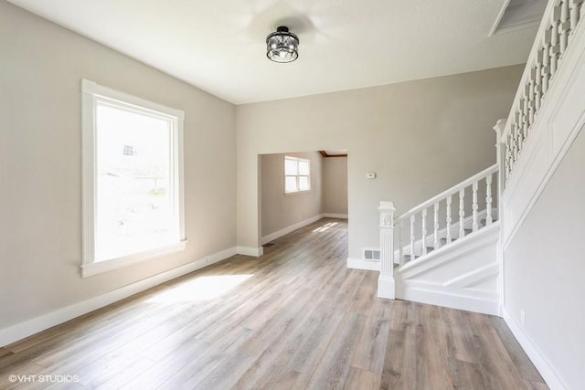 spare room featuring stairs, wood finished floors, and baseboards