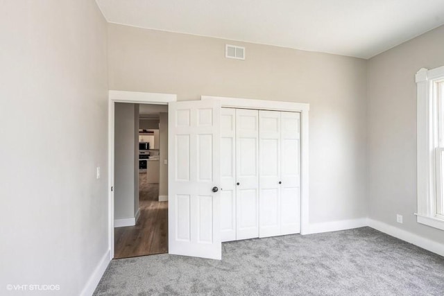 unfurnished bedroom with carpet flooring, baseboards, and a closet