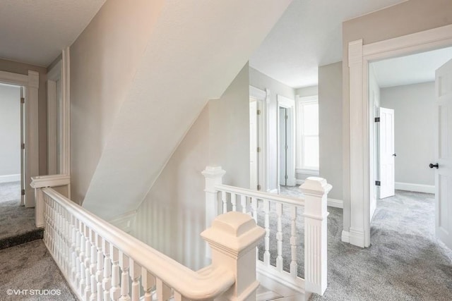 hallway featuring an upstairs landing, carpet, and baseboards