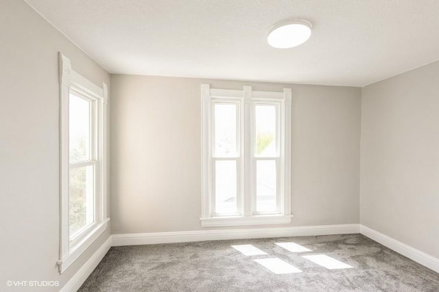 empty room featuring carpet floors, baseboards, and healthy amount of natural light