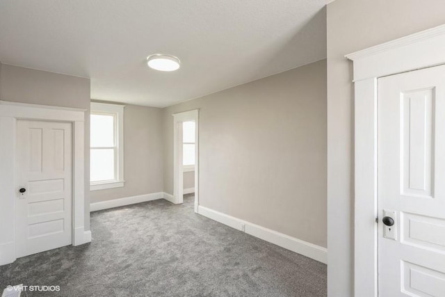 carpeted empty room featuring baseboards