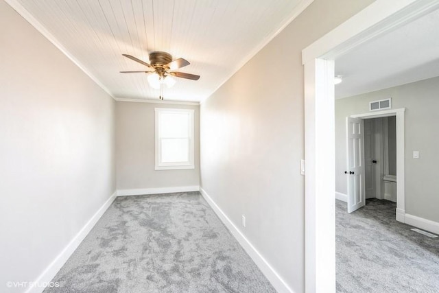 empty room featuring carpet flooring, a ceiling fan, baseboards, ornamental molding, and wood ceiling