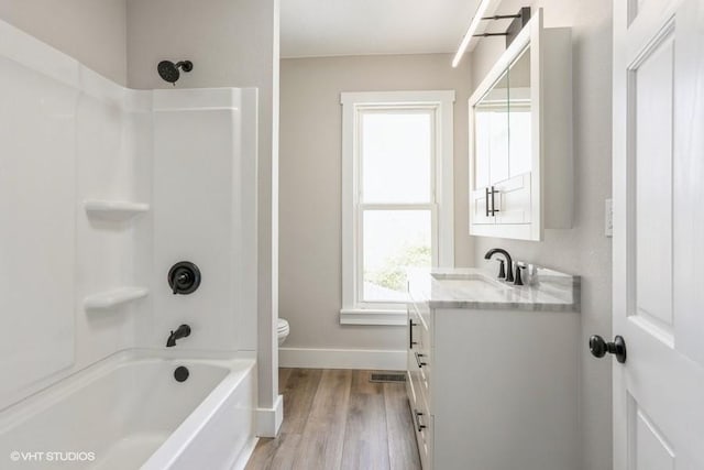 full bathroom with toilet, vanity, wood finished floors, shower / bathtub combination, and baseboards