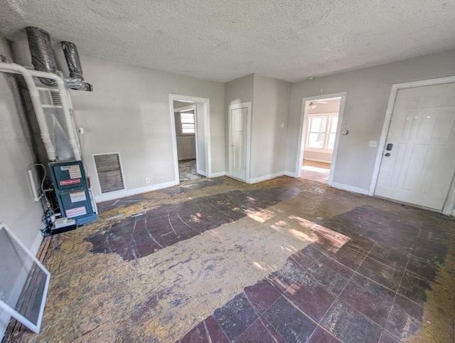 unfurnished living room with a textured ceiling and baseboards