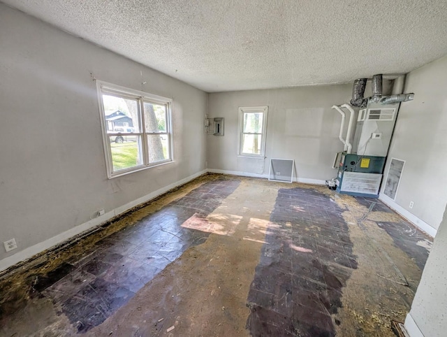 unfurnished living room featuring heating unit, a textured ceiling, and baseboards