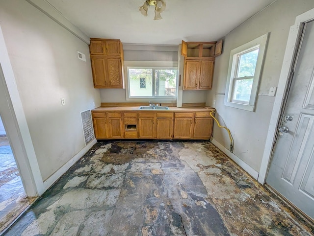 kitchen featuring baseboards, brown cabinets, a sink, and open shelves