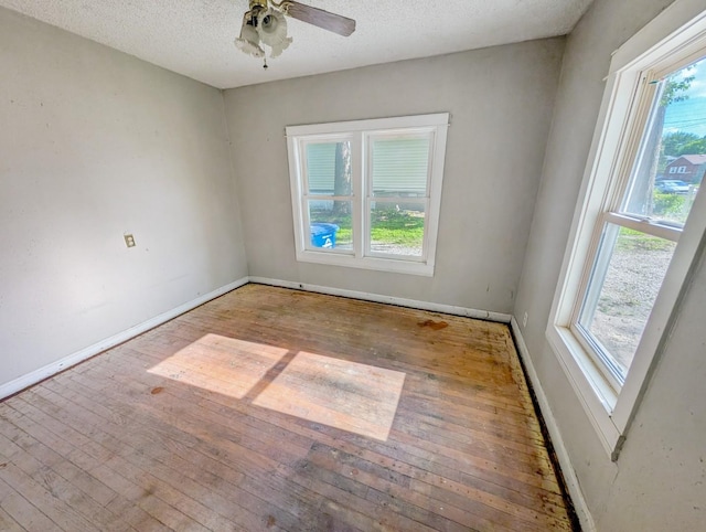 unfurnished room featuring hardwood / wood-style floors, plenty of natural light, baseboards, and a textured ceiling