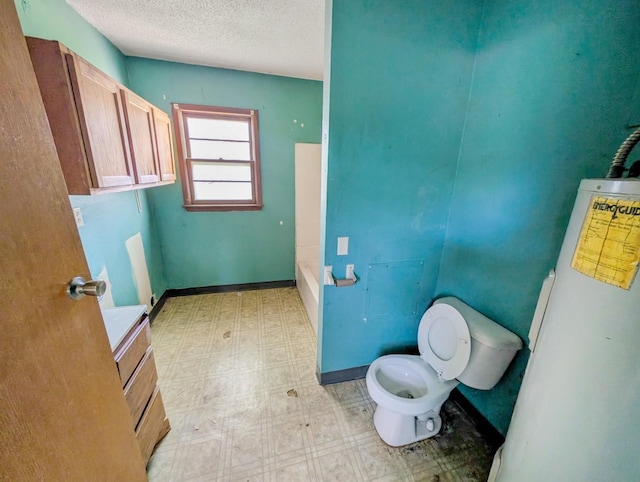 bathroom featuring tile patterned floors, toilet, a bath, a textured ceiling, and water heater