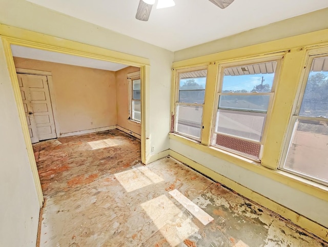 unfurnished room featuring a ceiling fan and baseboards