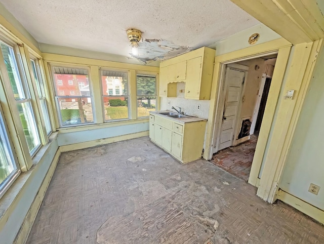 kitchen featuring a sink, plenty of natural light, a textured ceiling, light countertops, and cream cabinets